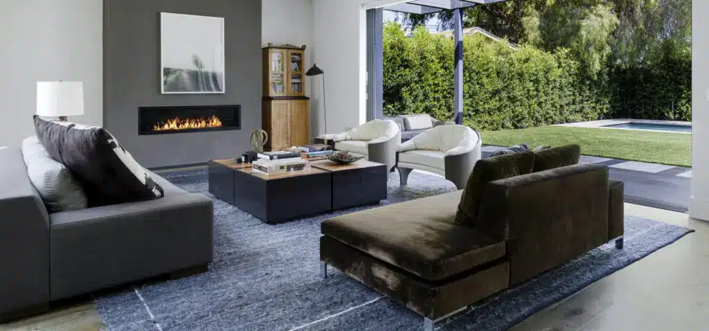 Should You Allow Pets in Your Short-Term Rental? 1 Modern living room with a fireplace and large windows overlooking a garden