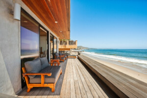 Beachfront property with wooden deck, outdoor seating, and ocean view