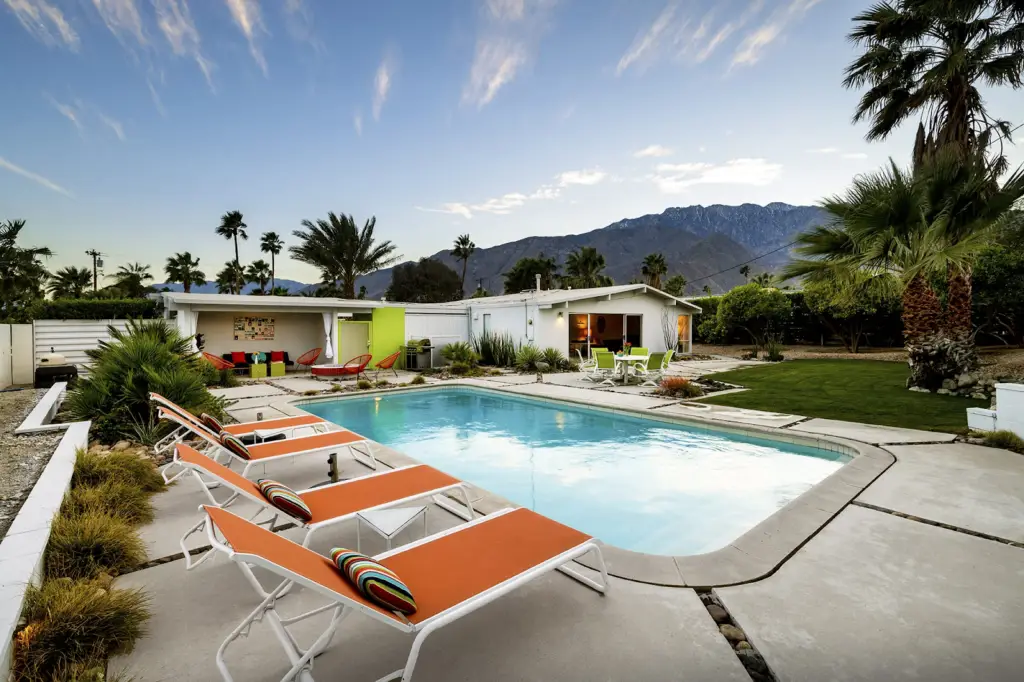 House of the Sun in Palm Springs by Open Air Homes - Outdoor pool area with a modern house, palm trees, and a mountain backdrop