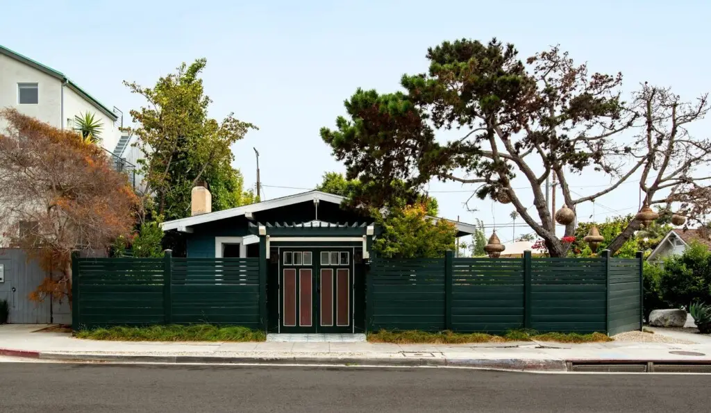 Exterior of a dark green rental property with a fence by Open Air Homes