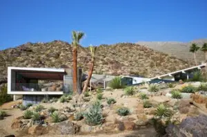 Modern house in a desert landscape with rocky hills and palm trees