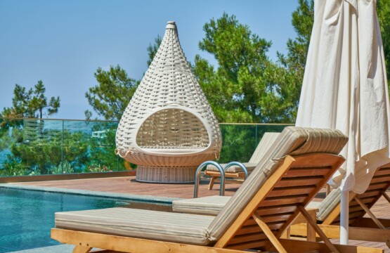 Pool area with sun loungers and white wicker chair