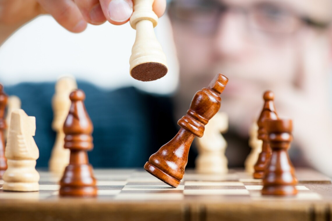 Chessboard with pieces being moved by a hand