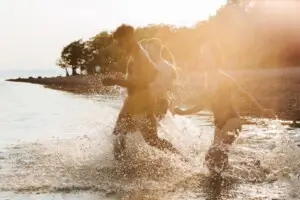 People running through water on a beach, capturing a joyful moment during a Labor Day getaway in Los Angeles and Palm Springs by Open Air Homes