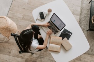 Woman working on a laptop with books and coffee