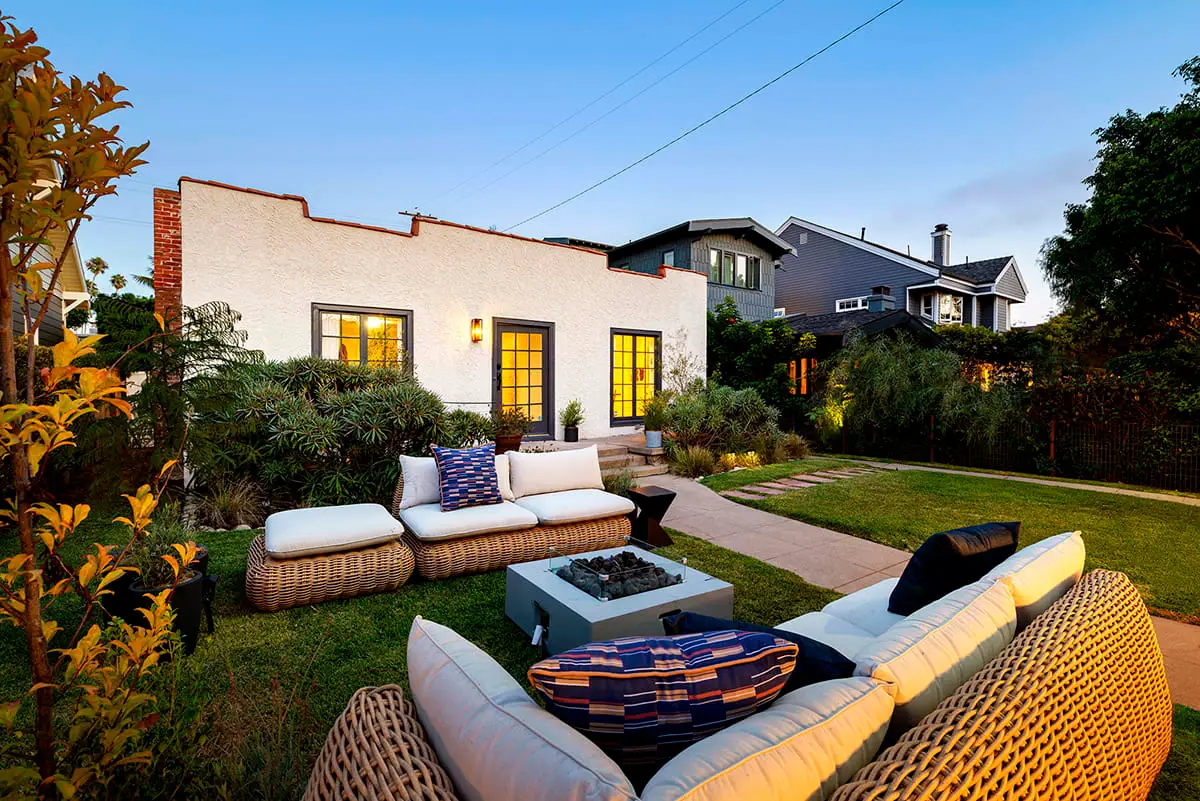 Outdoor seating area with wicker furniture and fire pit in a landscaped garden.