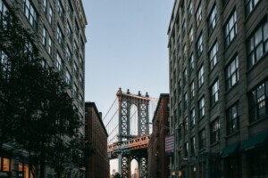 City street with tall buildings and a bridge in the background, associated with 'The Dangerous Rise of Underground Short-Term Rentals' article – by Open Air Homes.