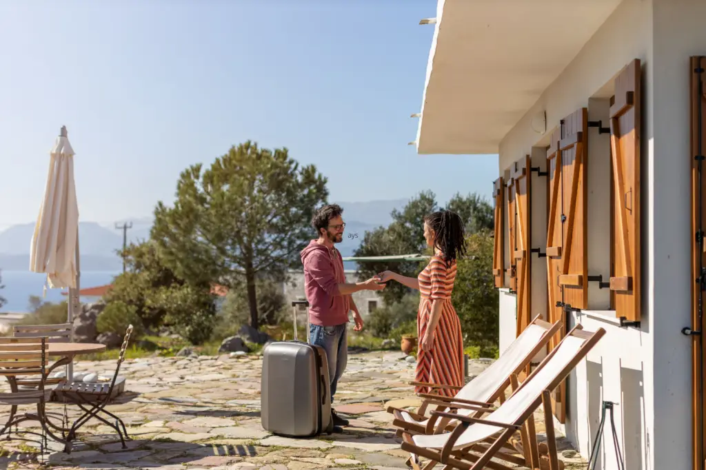 Man and woman greeting outdoors with a suitcase and scenic background - by Open Air Homes.