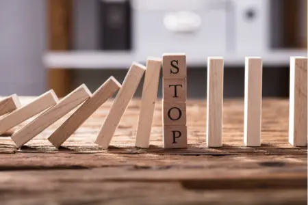 Wooden blocks falling with the word STOP visible