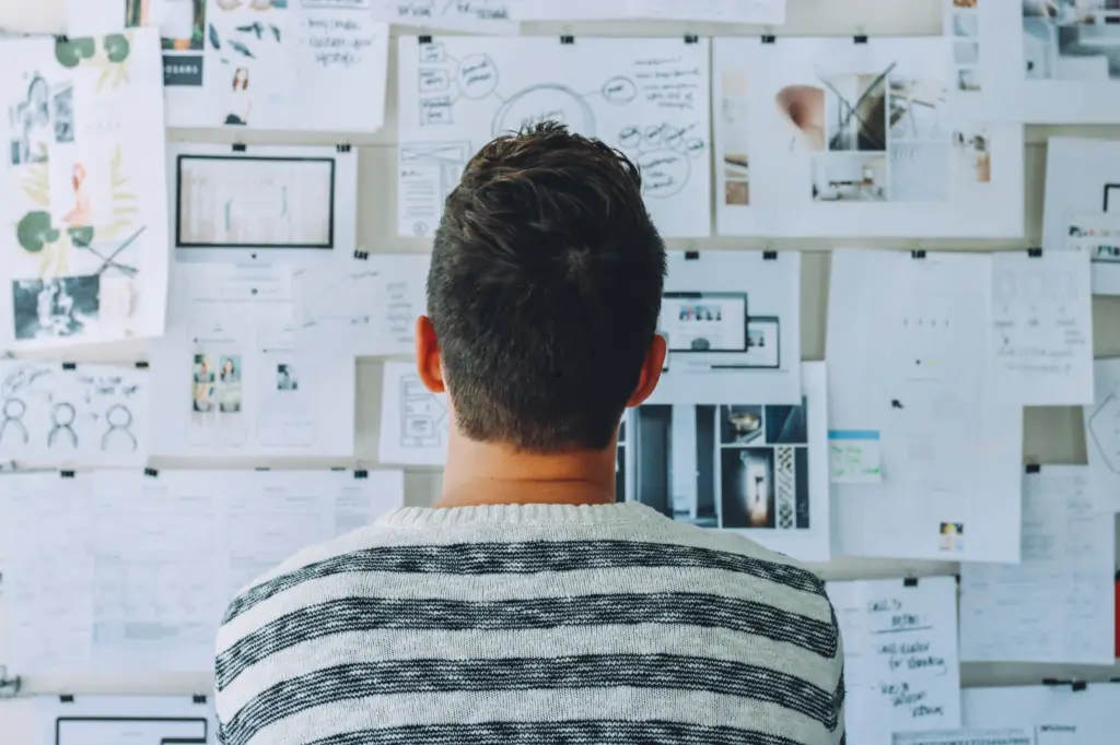 Person looking at a board filled with notes and images, representing planning and organization – Open Air Homes.