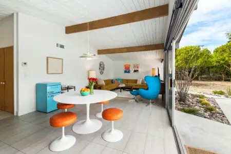 Living area with dining table, stools, sofa, and garden view in a short-term rental property - by Open Air Homes.
