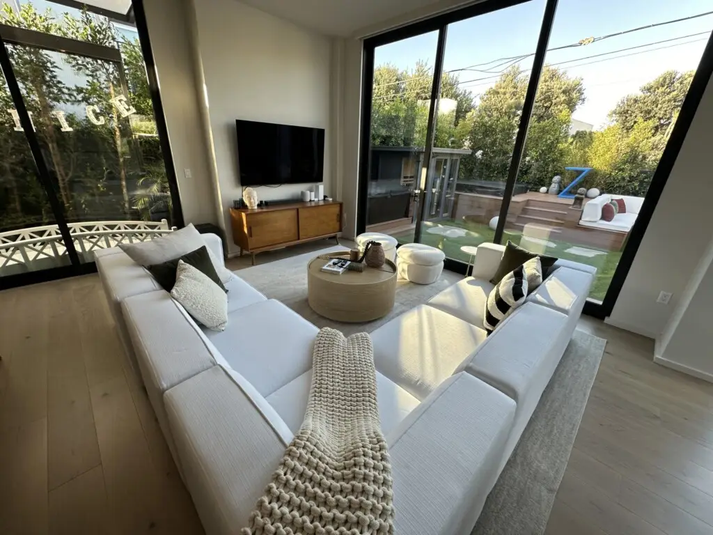 Introducing Zenice: Your Luxurious Airbnb Oasis in Venice Beach 1 Living room with modern furniture, large TV, and sliding door leading to an outdoor area – by Open Air Homes.