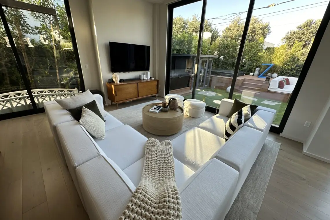 Living room with modern furniture, large TV, and sliding door leading to an outdoor area – by Open Air Homes.