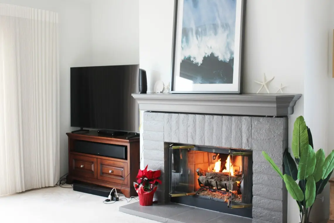 Living room with a fireplace, TV, and plants in a cozy setting at Mar Vista Sun-Drenched Spanish Manor - by Open Air Homes.