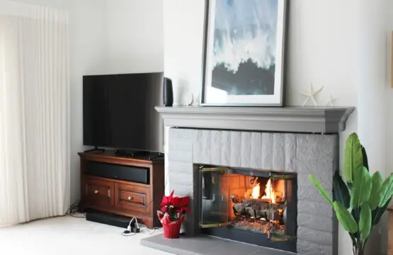 Living room with a fireplace, TV, and plants in a cozy setting at Mar Vista Sun-Drenched Spanish Manor - by Open Air Homes.