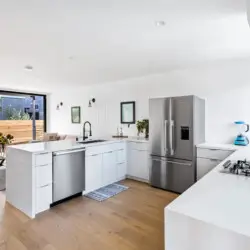 Modern kitchen with white cabinetry, gas cooktop, and wooden countertop at Westminster Bungalow - by Open Air Homes.