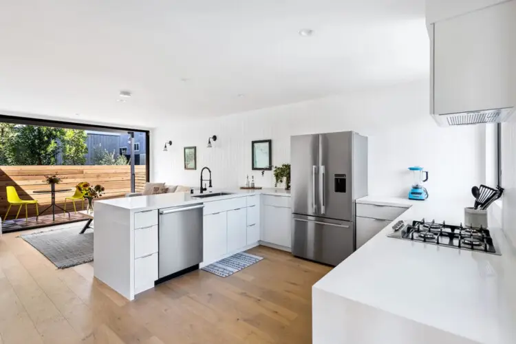 Modern kitchen with white cabinetry, gas cooktop, and wooden countertop at Westminster Bungalow - by Open Air Homes.