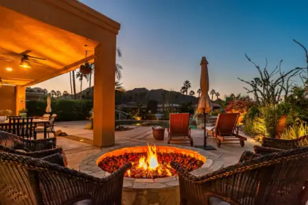 Outdoor patio at dusk with fire pit, chairs, and covered seating area at Lakeside La Quinta - by Open Air Homes