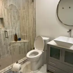 Bathroom with toilet, vanity, and glass shower at Desert Falls by Open Air Homes.