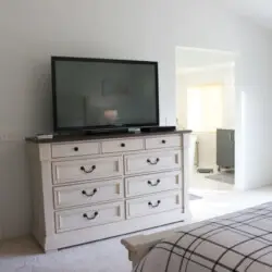 Bedroom with dresser, TV, and view of another room at Desert Falls by Open Air Homes.