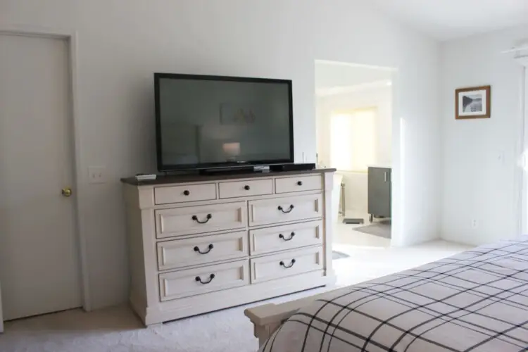 Bedroom with dresser, TV, and view of another room at Desert Falls by Open Air Homes.