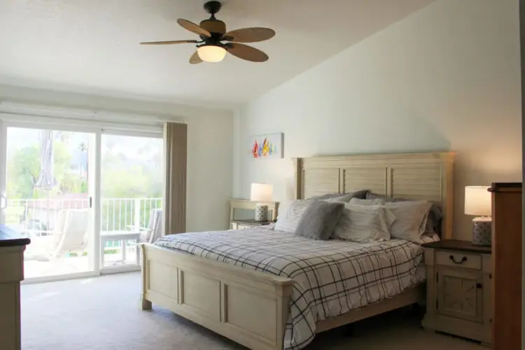 Bedroom with large bed, nightstands, and balcony access at Desert Falls by Open Air Homes.