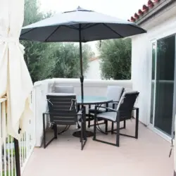 Outdoor patio with table, chairs, and umbrella at Desert Falls by Open Air Homes: Family Home in Gat.