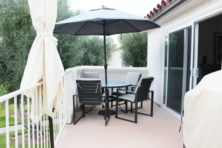 Outdoor patio with table, chairs, and umbrella at Desert Falls by Open Air Homes: Family Home in Gat.