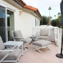 Outdoor seating area with chairs and table on a balcony at Desert Falls - by Open Air Homes