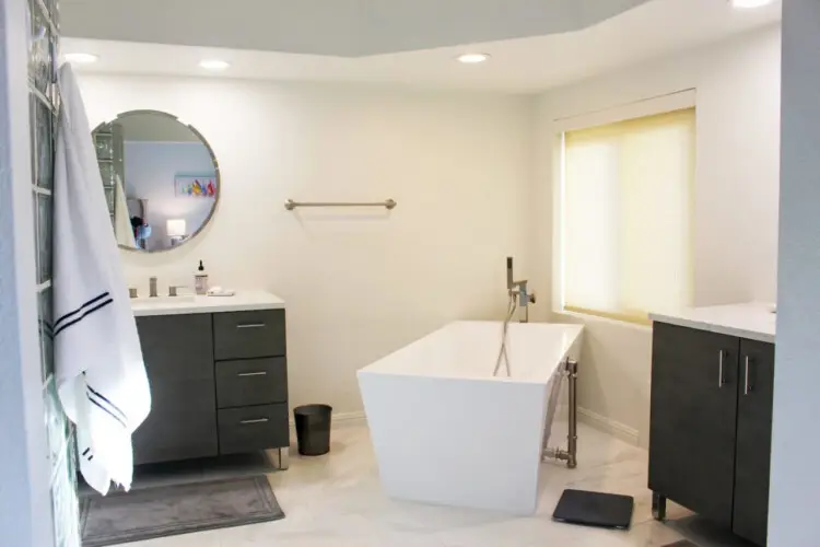 Bathroom with freestanding bathtub, vanity, and mirror at Desert Falls by Open Air Homes.