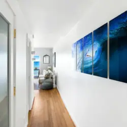 Hallway with wooden floors and blue artwork at Breathe Malibu - Ocean Front Condo w/ Beach Access by Open Air Homes.