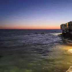 Ocean view at sunset with beach houses at Breathe Malibu - Ocean Front Condo w/ Beach Access by Open Air Homes.