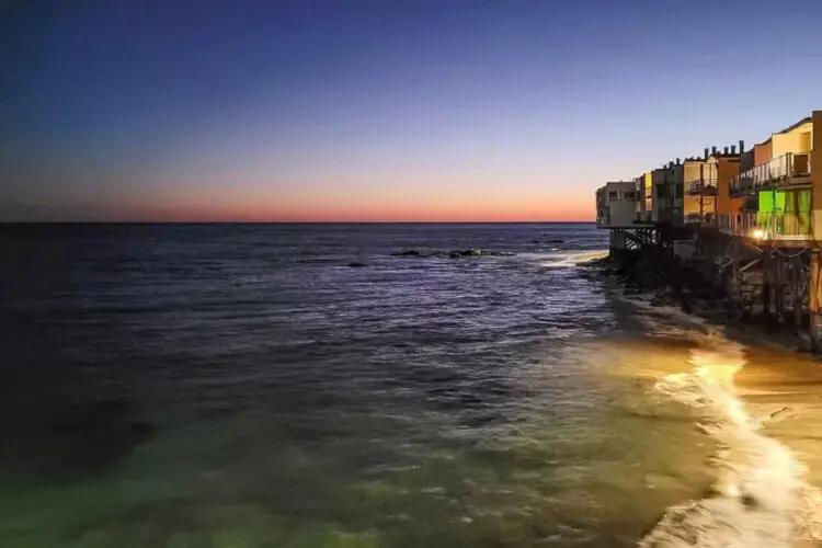 Ocean view at sunset with beach houses at Breathe Malibu - Ocean Front Condo w/ Beach Access by Open Air Homes.