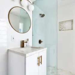 Bathroom with white vanity, round mirror, and glass shower at Breathe Malibu - Ocean Front Condo w/ Beach Access by Open Air Homes.