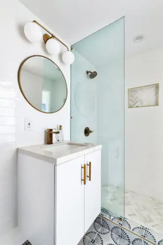 Bathroom with white vanity, round mirror, and glass shower at Breathe Malibu - Ocean Front Condo w/ Beach Access by Open Air Homes.