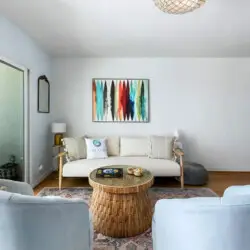 Living room with white sofa, armchairs, and wicker coffee table at Breathe Malibu - Ocean Front Condo w/ Beach Access by Open Air Homes.