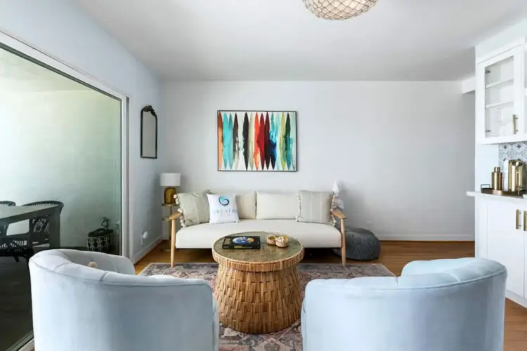 Living room with white sofa, armchairs, and wicker coffee table at Breathe Malibu - Ocean Front Condo w/ Beach Access by Open Air Homes.