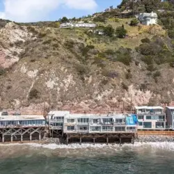 Oceanfront houses on stilts along the coastline at Breathe Malibu - Ocean Front Condo w/ Beach Access by Open Air Homes.