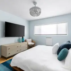 Bedroom with white bed, blue patterned wallpaper, and blue rug at Breathe Malibu - Ocean Front Condo w/ Beach Access by Open Air Homes.