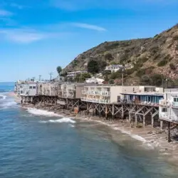 Oceanfront houses on stilts along the coastline at Breathe Malibu - Ocean Front Condo w/ Beach Access by Open Air Homes.