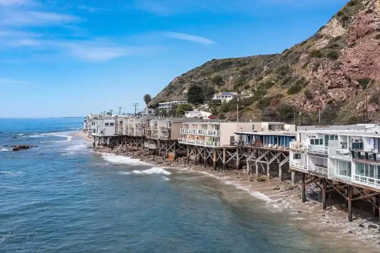 Oceanfront houses on stilts along the coastline at Breathe Malibu - Ocean Front Condo w/ Beach Access by Open Air Homes.