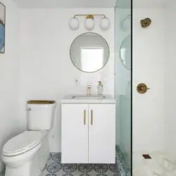 Bathroom with white vanity, round mirror, and glass shower at Breathe Malibu - Ocean Front Condo w/ Beach Access by Open Air Homes.