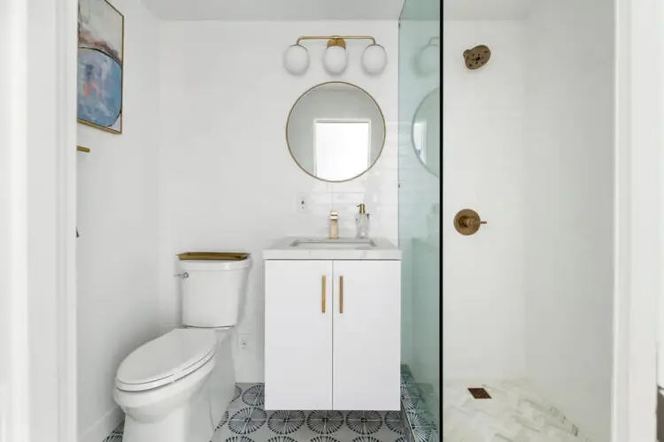 Bathroom with white vanity, round mirror, and glass shower at Breathe Malibu - Ocean Front Condo w/ Beach Access by Open Air Homes.