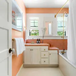 Bathroom with orange walls, white vanity, and glass shower at Charming Walk Street Hideaway in Venice Beach by Open Air Homes.