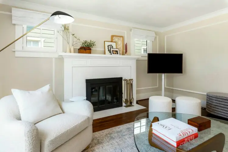 Living area with fireplace, wall-mounted TV, and white armchair at Charming Walk Street Hideaway in Venice Beach by Open Air Homes.