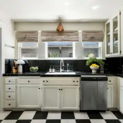 Kitchen with black and white checkeKitchen with black and white checkered flooring, white cabinets, and window at Charming Walk Street Hideaway in Venice Beach by Open Air Homes.red flooring and white cabinets at Charming Walk Street Hideaway - by Open Air Homes