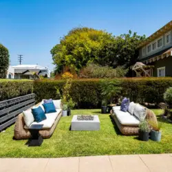 Outdoor seating area with wicker furniture and fire pit in garden at Charming Walk Street Hideaway in Venice Beach by Open Air Homes.