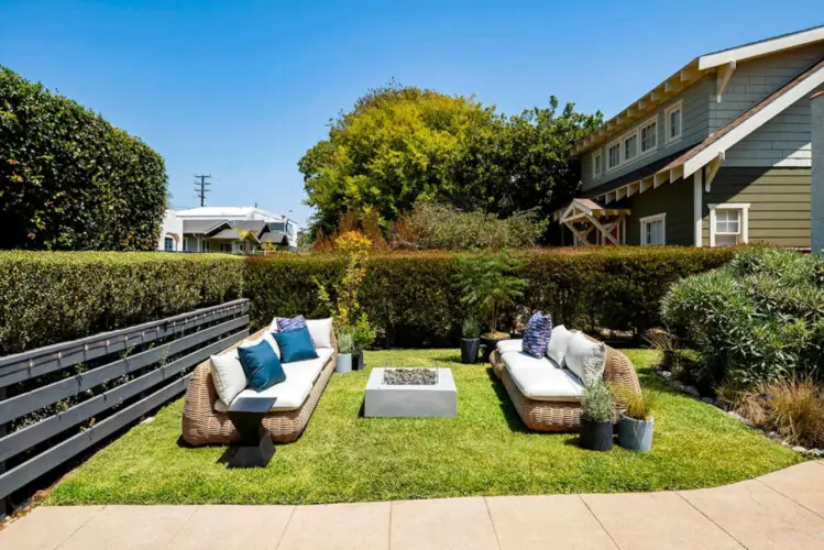 Outdoor seating area with wicker furniture and fire pit in garden at Charming Walk Street Hideaway in Venice Beach by Open Air Homes.