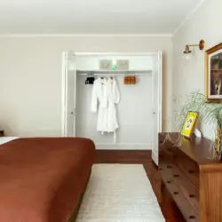 Bedroom with open closet, wooden dresser, and bed at Charming Walk Street Hideaway in Venice Beach by Open Air Homes.