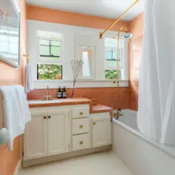 Bathroom with orange tiles, bathtub, and sink at Charming Walk Street Hideaway in Venice Beach by Open Air Homes.